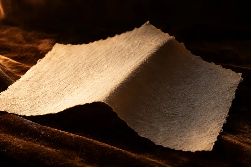 Zgięty wzdłuż papier czerpany, cień w załamaniu, ciepłe światło